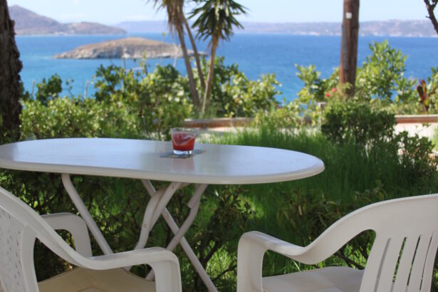 White table and white chairs set in garden with sea backdrop